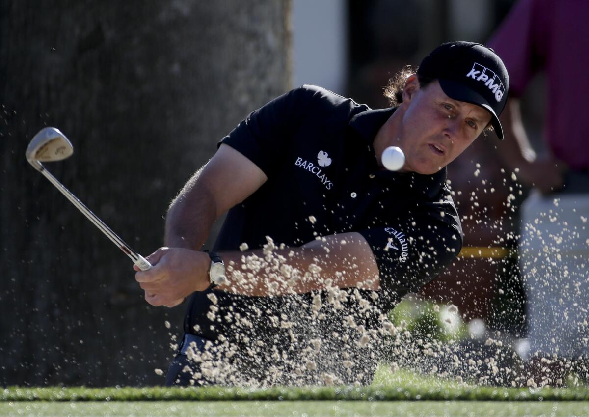 Phil Mickelson watches his shot from the bunker on the fourth hole Thursday during the Humana Challenge golf tournament.