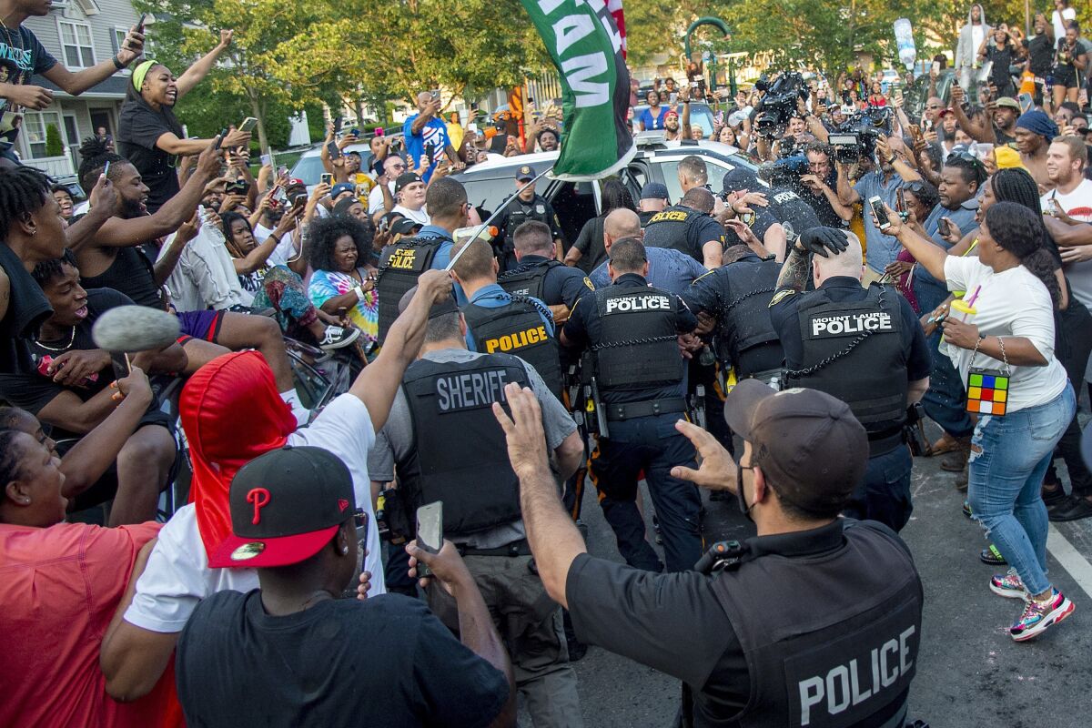 Police escort Edward Cagney Mathews through a crowd of people who had gathered outside his Mount Laurel, N.J., home, Monday, July 5, 2021. Mathews, a white man who is being called racist after a video went viral of him pushing a Black neighbor with his chest and using racist slurs to address the neighbor and others, was arrested Monday after protesters gathered at his home for hours. (Tom Gralish/The Philadelphia Inquirer via AP)