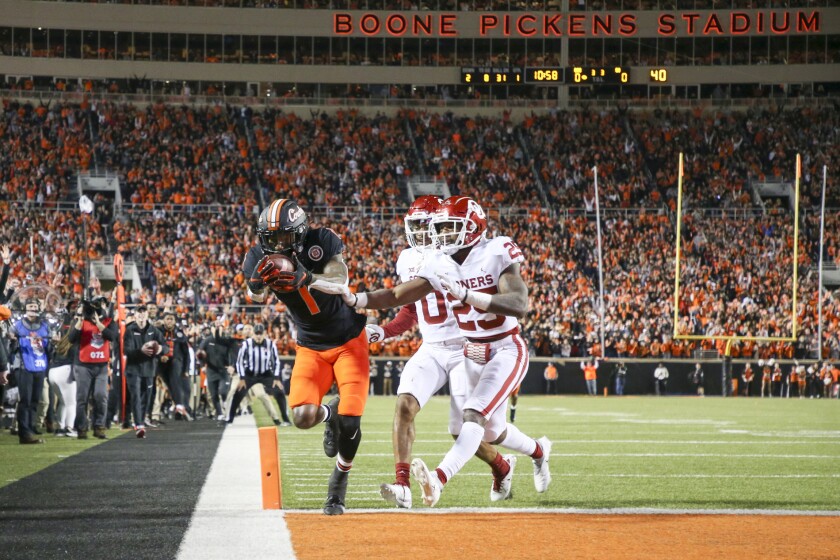 Oklahoma State wide receiver Tay Martin (1) catches a touchdown pass next to Oklahoma cornerback Woodi Washington (0) and defensive back Justin Broiles (25) during an NCAA college football game in Stillwater, Okla., Saturday, Nov. 27, 2021. (Ian Maule/Tulsa World via AP)