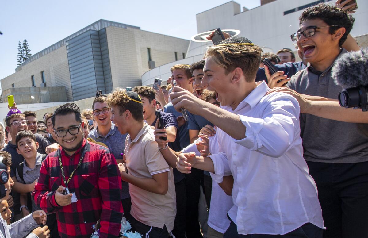 A teacher walks among a cheering crowd of his students.