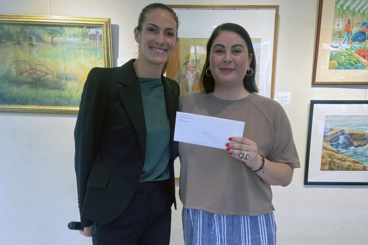 Jenna Novotny (left), director of development at Mama’s Kitchen, accepts a check from Kiwanis Club member Nancy Walters.