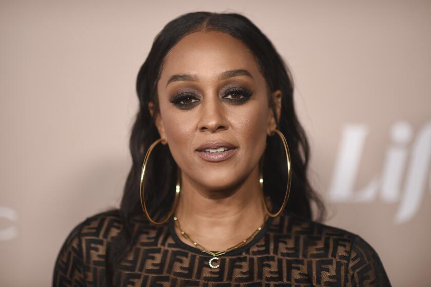 A woman with dark smoky eyeshadow wears large hoop earrings at an entertainment industry event