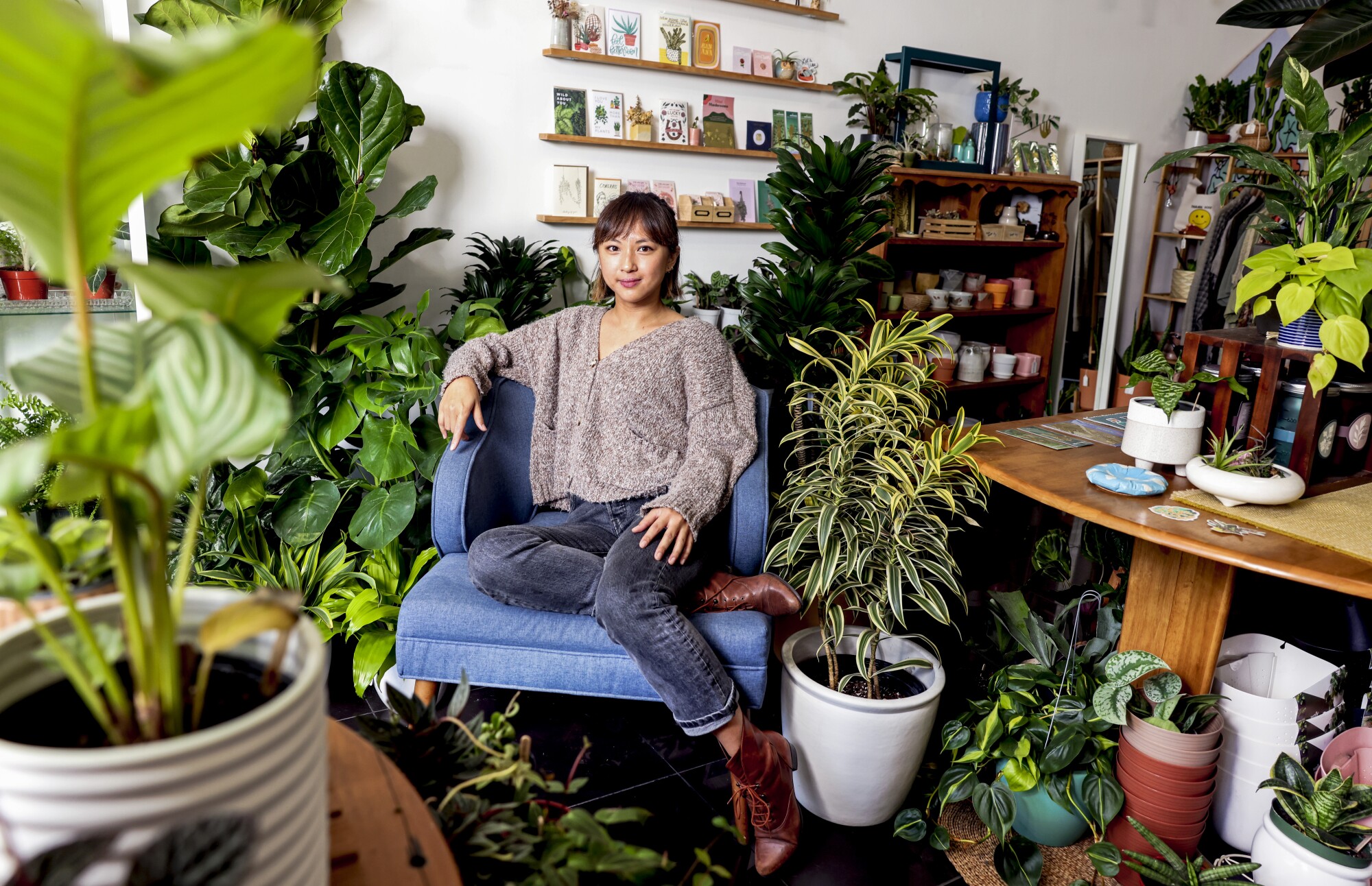 बेले डंकोंगकाकुल पौधों से घिरी कुर्सी पर बैठती हैं 
