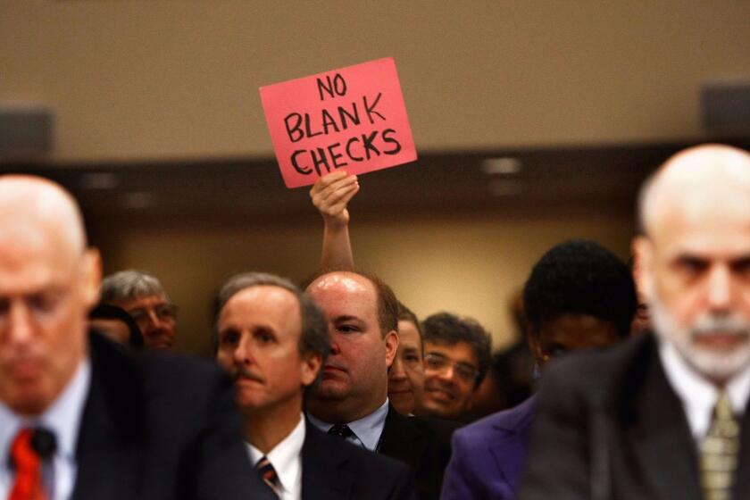 WASHINGTON - SEPTEMBER 23: A demonstrator holds up a sign behind U.S. Treasury Secretary Henry Paulson (L) and Federal Reserve Board Chairman Ben Bernanke (R) during a hearing before the Senate Banking, Housing and Urban Affairs Committee September 23, 2008 on Capitol Hill in Washington, DC. The Bush administration officials were testifying about a proposed $700 billion bailout that they hope will stabilize the faltering U.S. financial system. Many members of Congress have expressed anger at the plan they say will pay for Wall Street's mistakes at taxpayers' expense. (Photo by Chip Somodevilla/Getty Images) ORG XMIT: 82875236