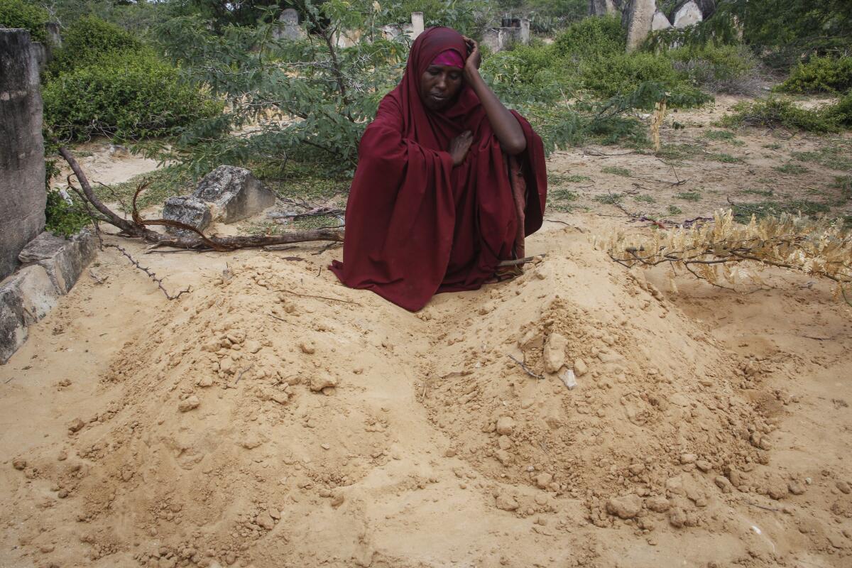 Fatuma Abdi Aliyow sits by the graves of her two sons who died of malnutrition-related diseases last week, at a camp for the displaced on the outskirts of Mogadishu, Somalia Saturday, Sept. 3, 2022. Millions of people in the Horn of Africa region are going hungry because of drought, and thousands have died, with Somalia especially hard hit because it sourced at least 90 percent of its grain from Ukraine and Russia before Russia invaded Ukraine. (AP Photo/Farah Abdi Warsameh)