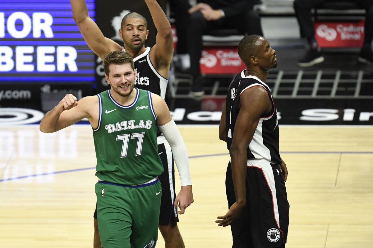 Dallas Mavericks guard Luka Doncic, bottom left, reacts after drawing a foul during the first half.