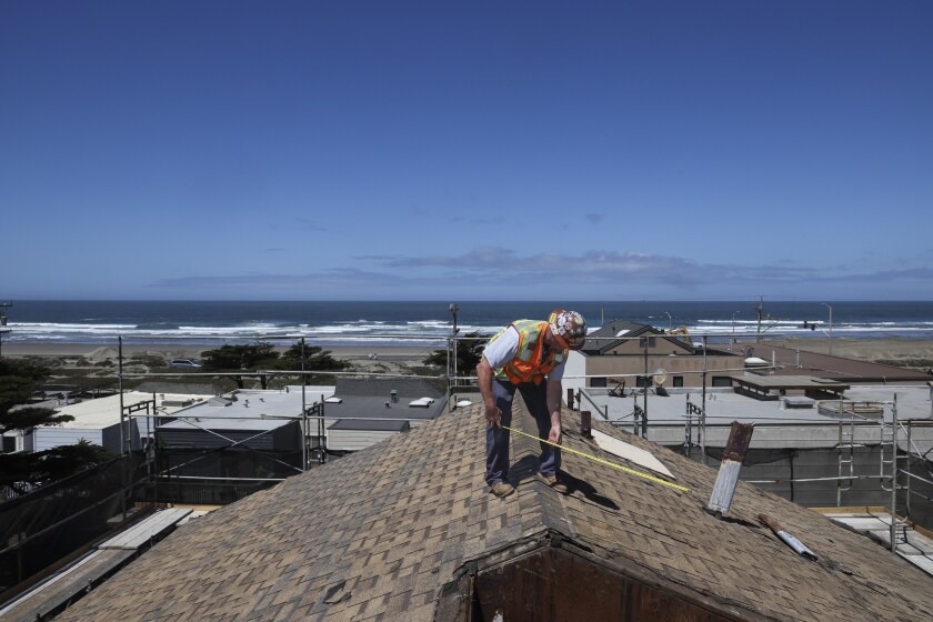 A man measures a roof of a low-income housing complex.