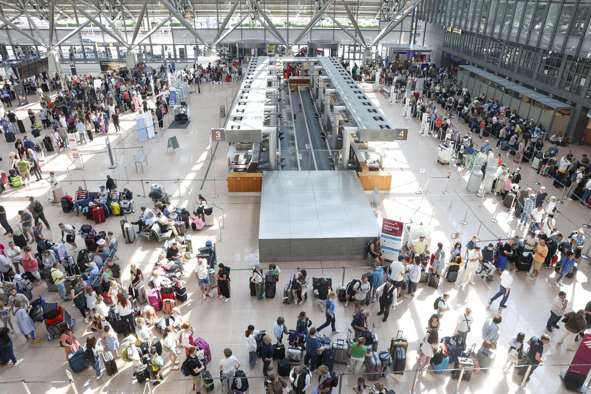 Travelers wait in Terminal 1 for check-in at Hamburg Airport, in Hamburg, Germany