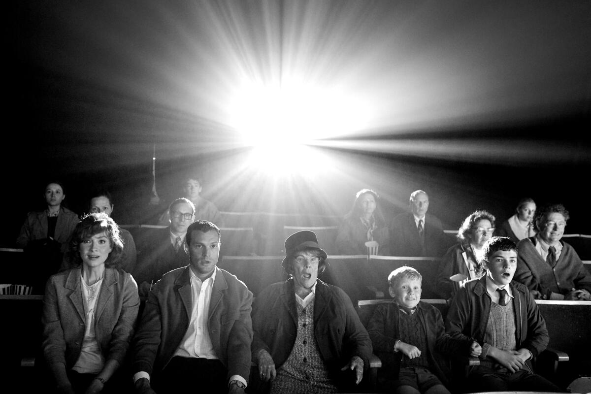 A black-and-white photo of people sitting in theater seats reacting to a movie 