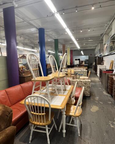 Dining room tables, sofas and dressers for sale at a thrift store. 