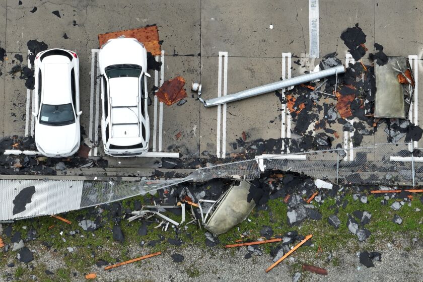 Aerial view of debris scattered near two white cars.