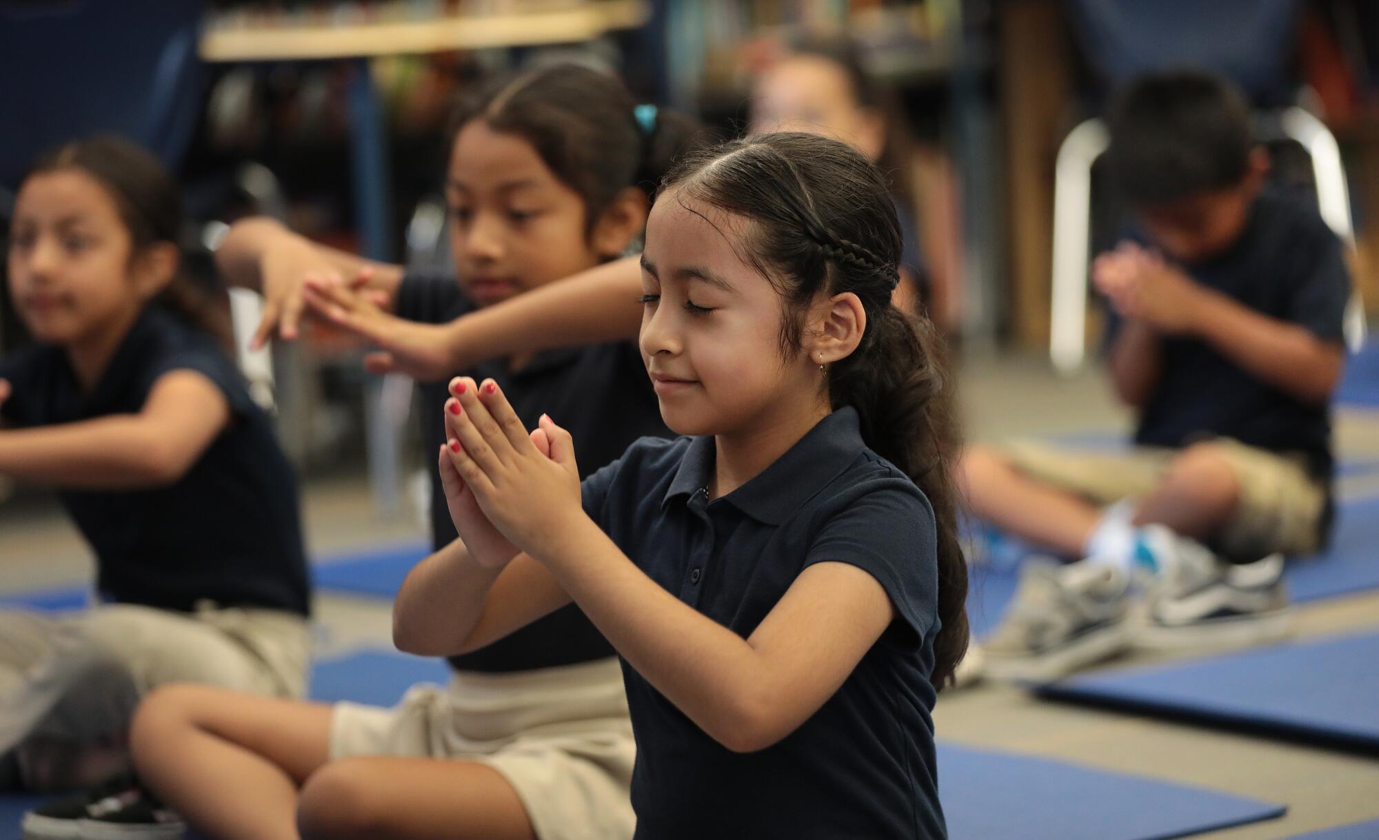 Second grade student Giselle Calderon stretches to instructions from Yoga instructor Sacha Taylor and Leah Gallegos