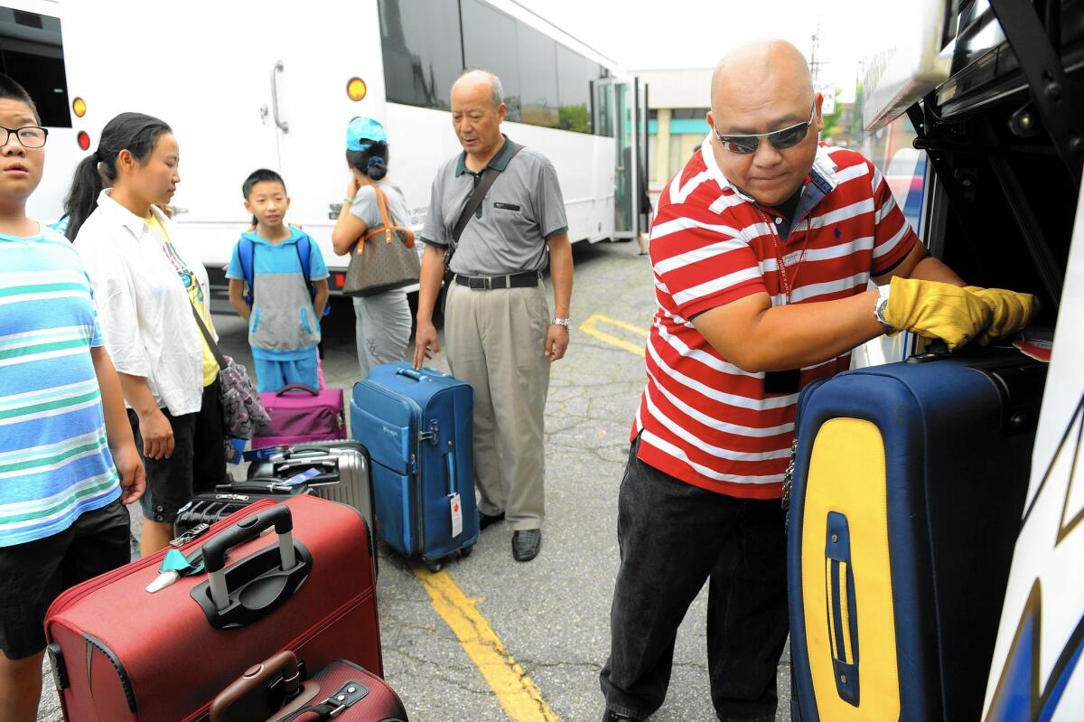 Bus driver Ramoncito Batac helps load passengers' luggage for a trip to Yellowstone National Park and Mt. Rushmore from America Asia Travel Center in Monterey Park.