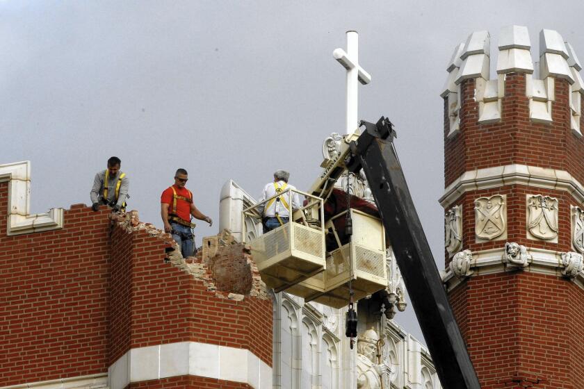 Maintenance workers inspect the damage to one of the spires on Benedictine Hall at St. Gregory's University after a magnitude-5 earthquake in Shawnee, Okla., in 2011.