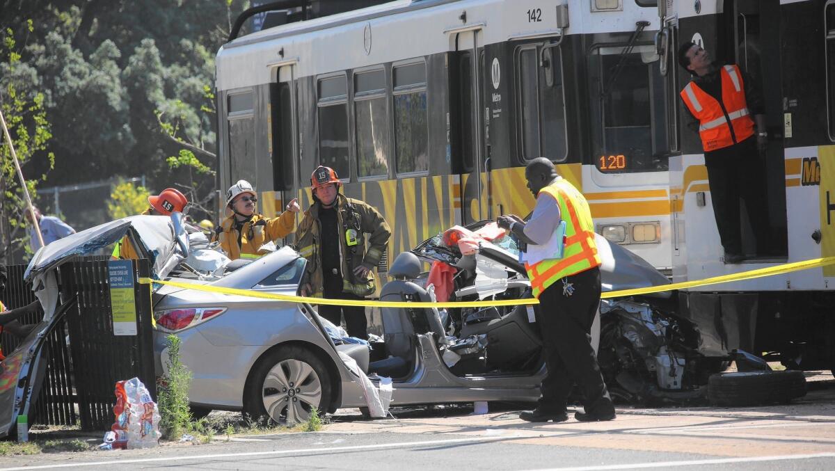 Emergency crews work to clear the site of a crash between a car and a Metro Expo Line train on Exposition Boulevard near USC.