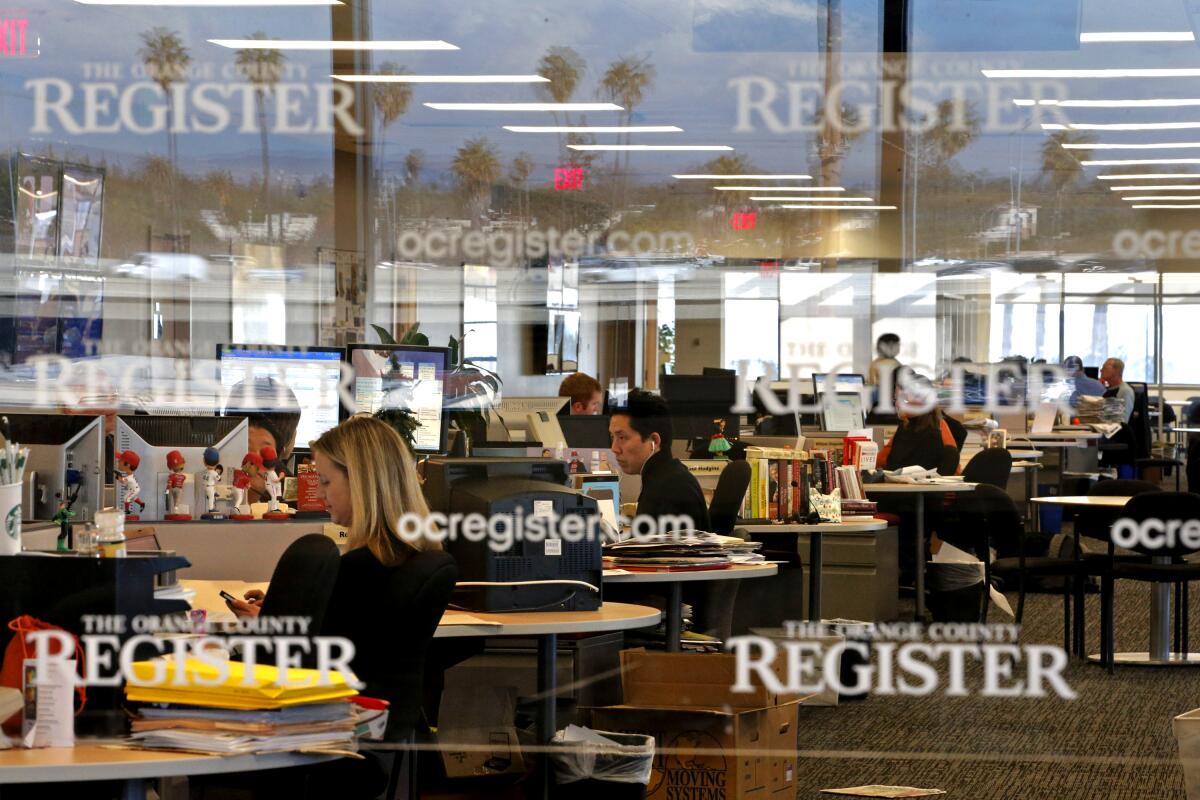 People work at computers inside the Orange County Register newsroom.