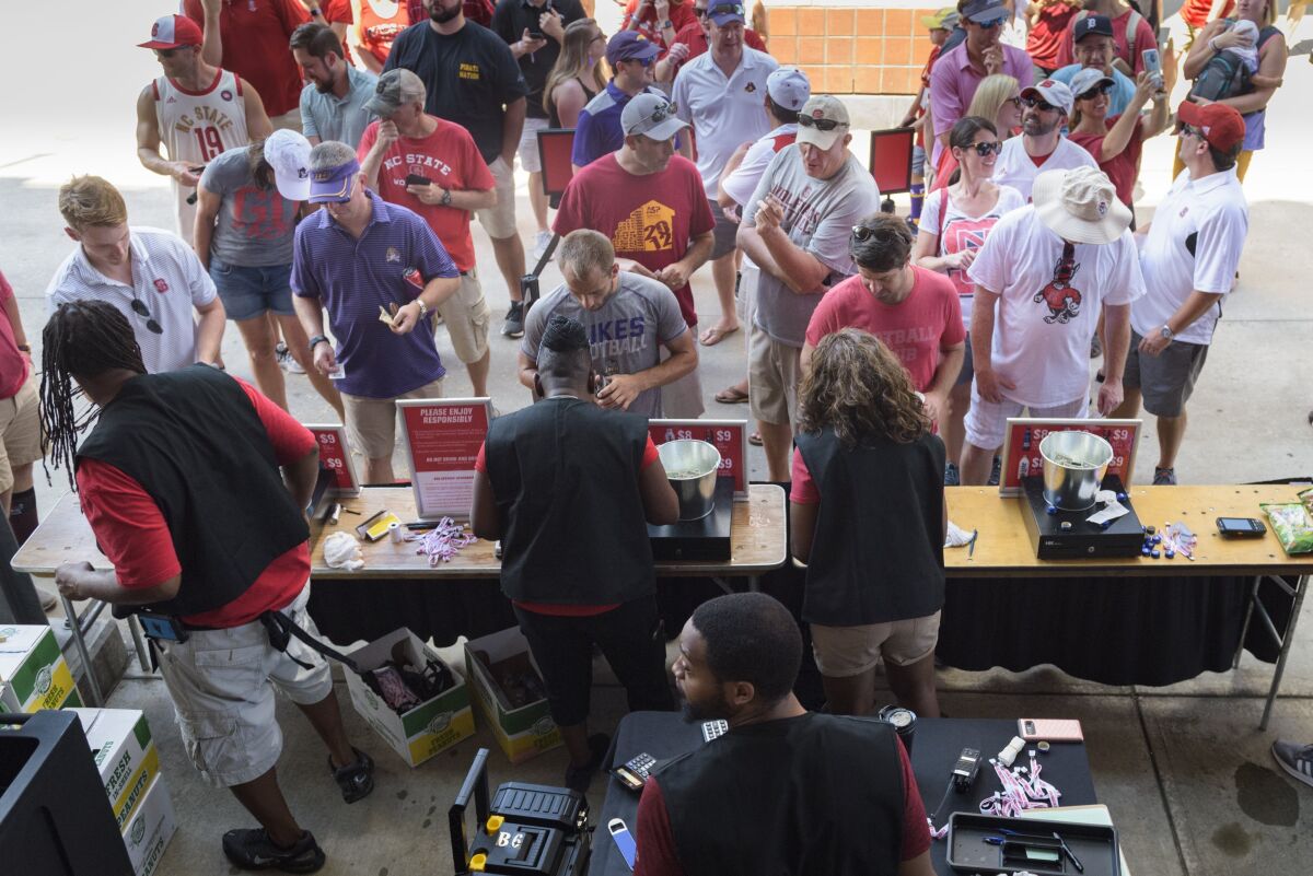 FILE - Fans line up at a concession stand that sells beer during an NCAA college football game between North Carolina State and East Carolina at Carter Finley Stadium in Raleigh, N.C., Saturday, Aug 31, 2019. Nebraska would sell alcohol at the Big Ten wrestling championships in March if university regents approve a policy revision at its meeting next week, opening the possibility of booze being available at Cornhuskers football games. Athletic department leaders have long considered selling alcohol at their venues, and their interest has increased recently as they've looked for ways to enhance the fan experience. (Bryan Cereijo/The News & Observer via AP, File)