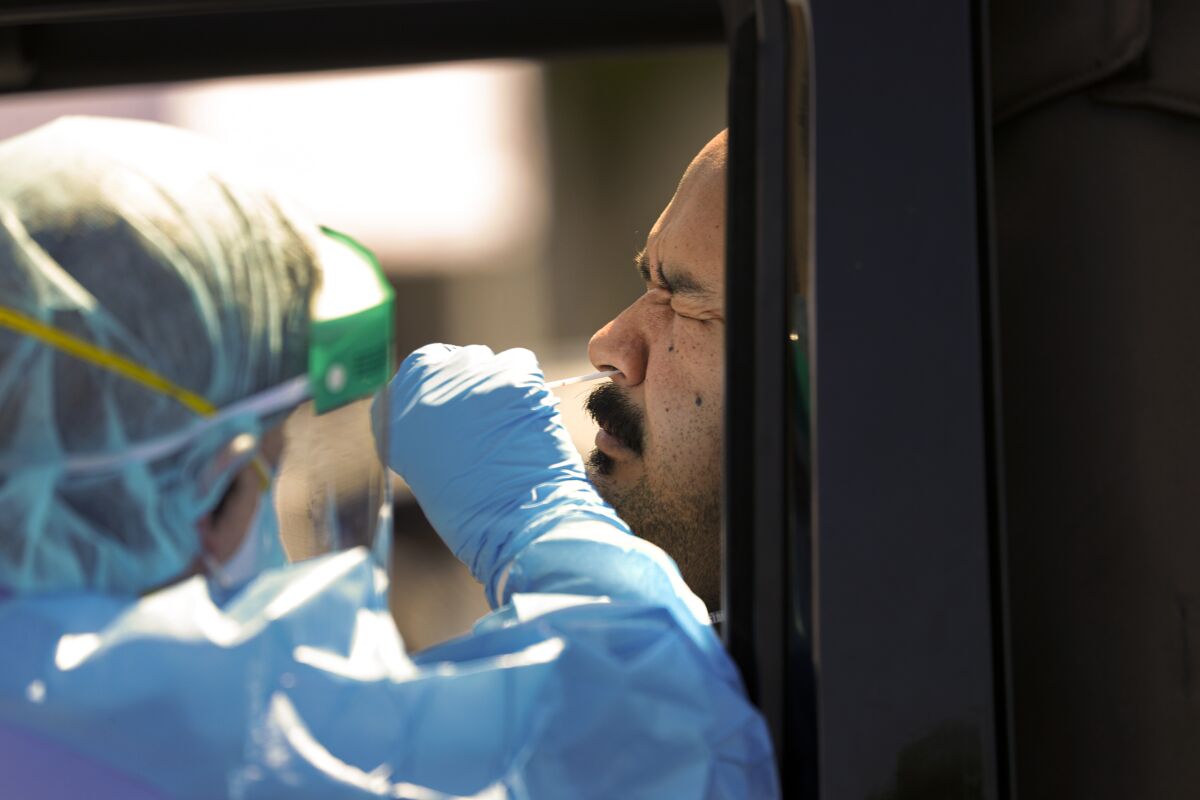 A healthcare worker collects a nasal swab from Victor Guardavo for coronavirus testing in San Bernardino County.