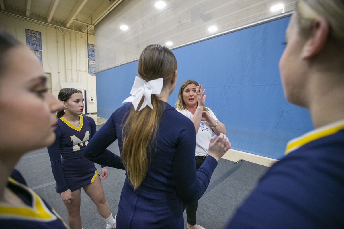 Marina High cheerleading coach Vraunwyn Denny speaks to team members during practice on Monday.