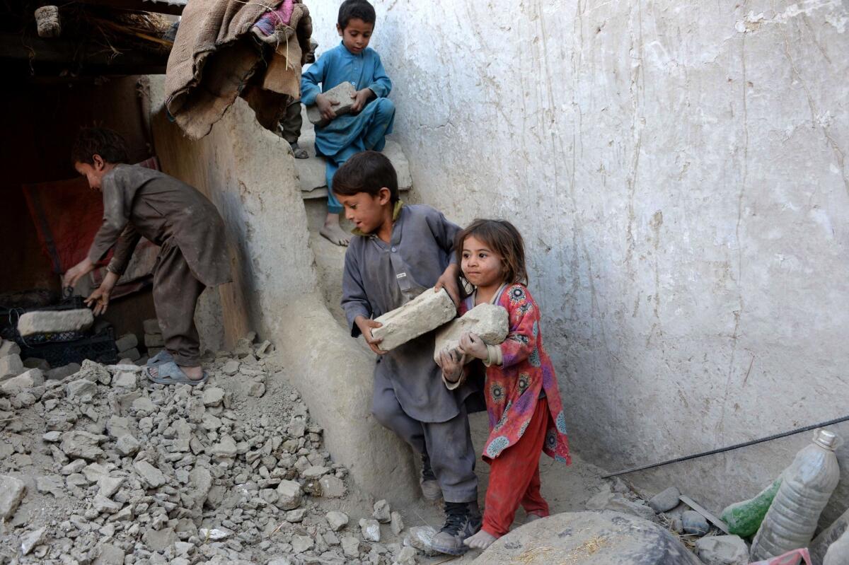 Children assist in rebuilding their earthquake-damaged home in Afghanistan's Nangarhar province on Oct. 29.