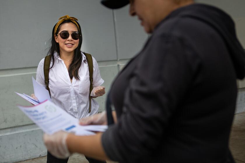 LOS ANGELES, CALIF. - MARCH 22, 2020: Cristin Lim, 27, of Mar Vista gives out flyers throughout Mar Vista and the Los Angeles Metropolitan area offering up help to people facing the coronavirus pandemic. on Sunday, March 22, 2020 in Los Angeles, Calif.. (Jason Armond / Los Angeles Times)