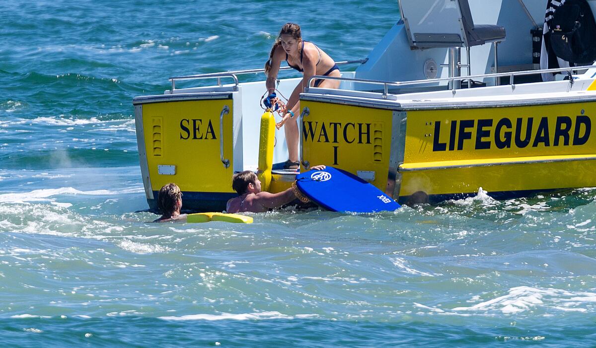 Newport Beach lifeguards pull a swimmer caught in a rip current to safety aboard the Sea Watch rescue boat Saturday.