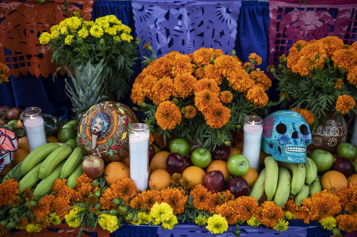 An ofrenda of candles, bright flowers and skull figures 
