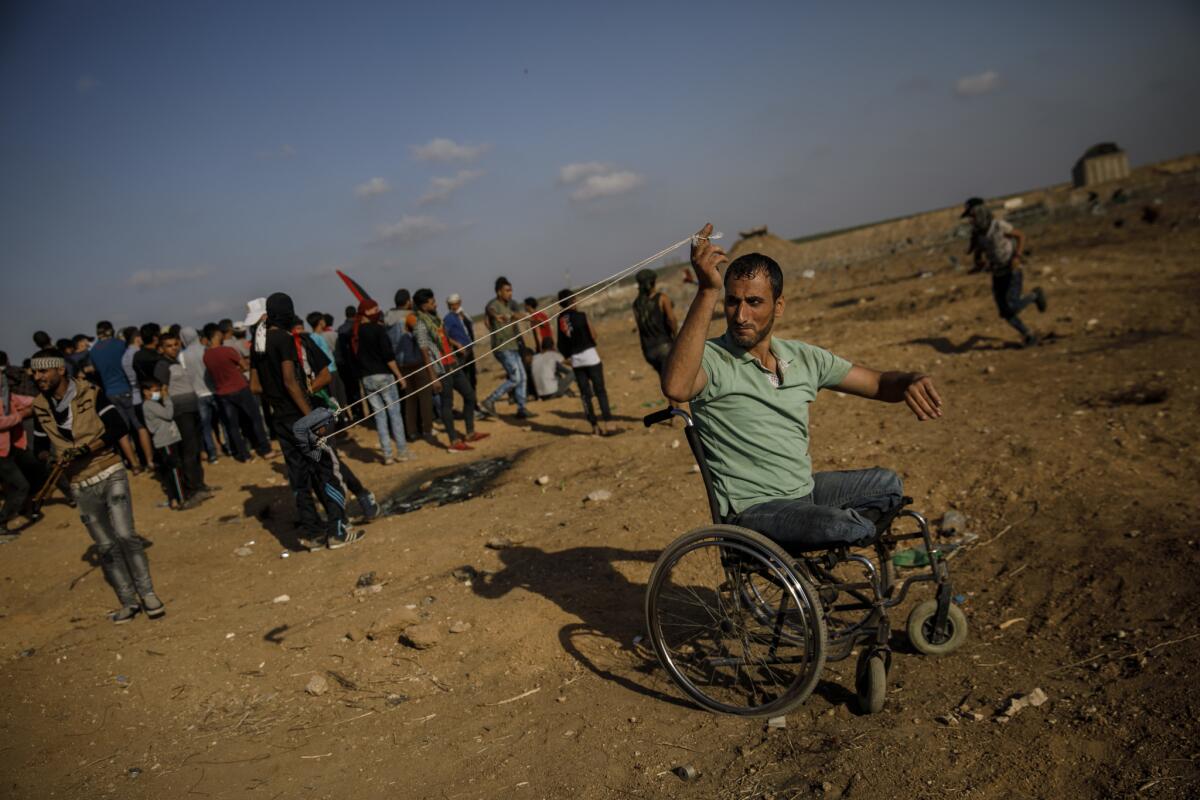 Sabir Ashqar, who said he lost his legs in the 2008-2009 Gaza war, slings a projectile at the border fence separating Israel and the Gaza Strip.