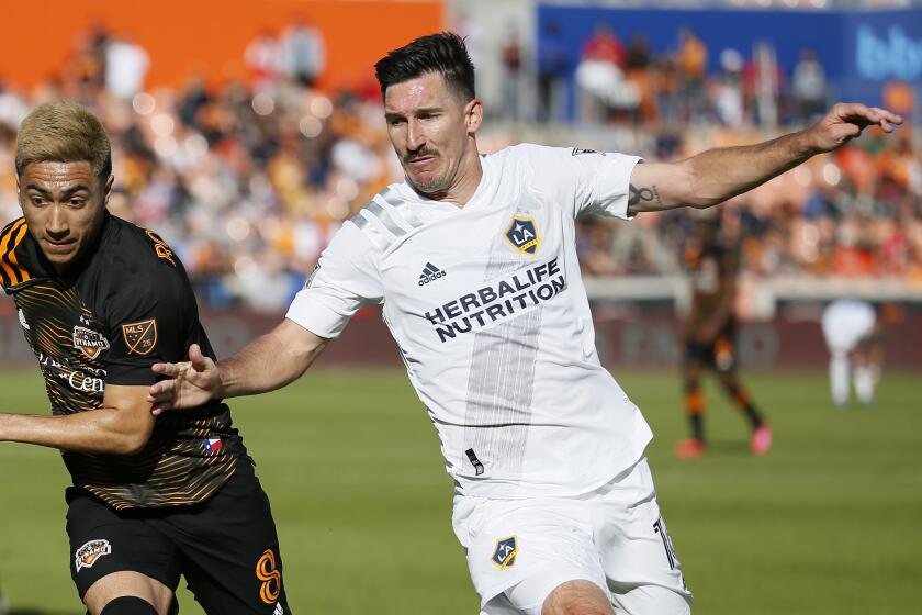 HOUSTON, TEXAS - FEBRUARY 29: Sacha Kljestan #16 of Los Angeles Galaxy races to get the ball before Memo Rodriguez #8 of Houston Dynamo at BBVA Stadium on February 29, 2020 in Houston, Texas. (Photo by Bob Levey/Getty Images)