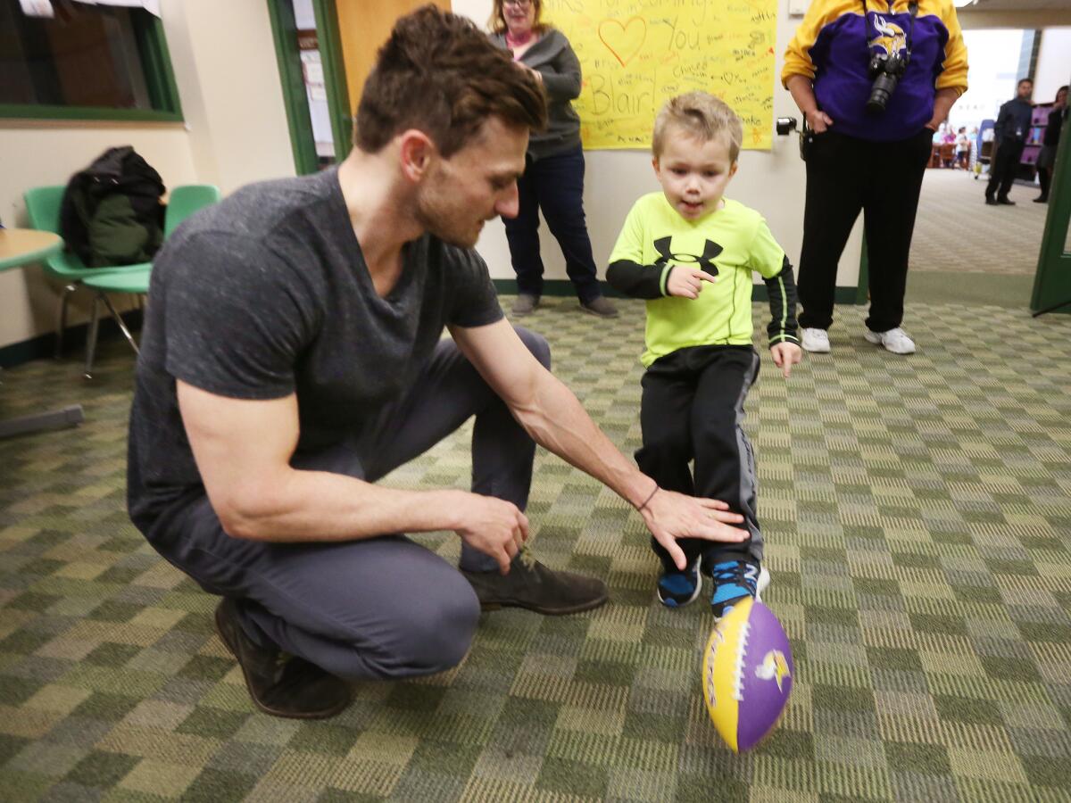 Max Birdwell, 4, kicks a football from the hold of Minnesota Vikings kicker Blair Walsh during the player's visit to Northpoint Elementary on Thursday.