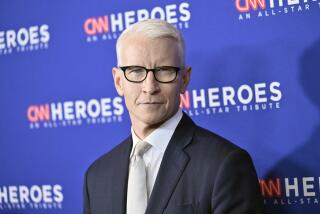 Anderson Cooper wears black-rimmed glasses and a suit and tie