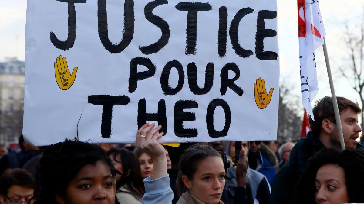 A demonstrator holds a sign reading "Justice for Theo," the name of the 22-year-old alleged rape victim, during a protest against alleged police abuse in Paris on Saturday.