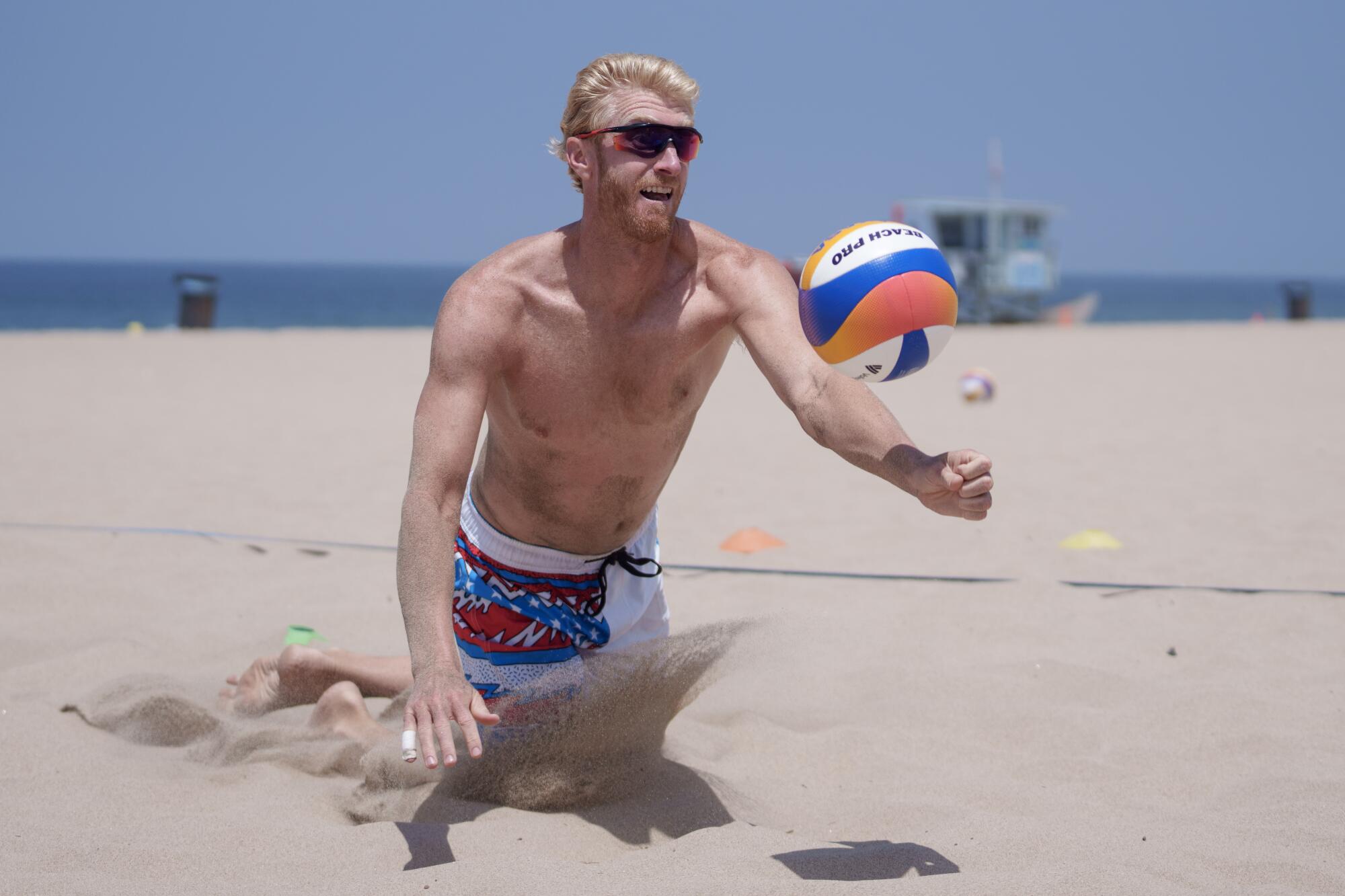 Beach volleyball player Chase Budinger diving for the ball while playing on the sand at Hermosa Beach