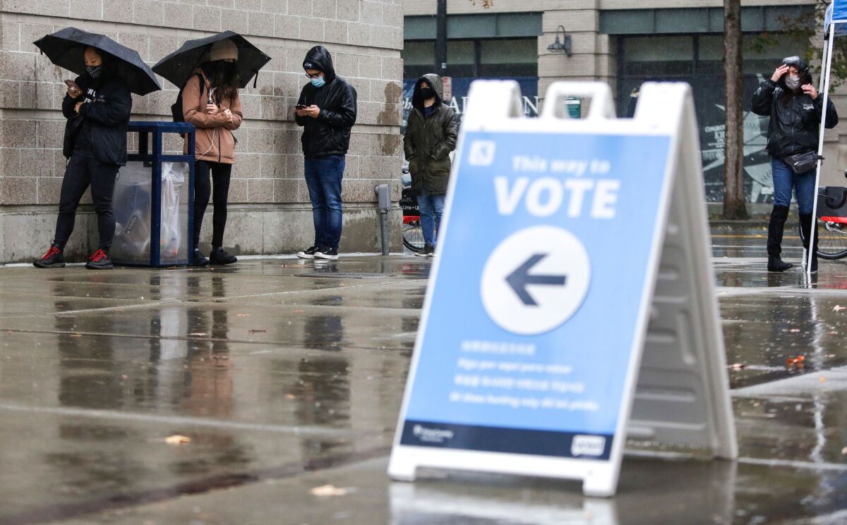 People line up in the rain on Election Day at a voting center set up at the CenturyLink Field Event Center.