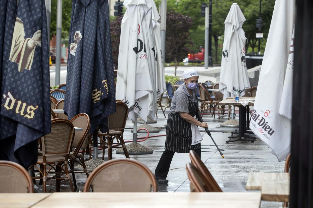 FILE - A worker at a restaurant along K Street in downtown Washington, power washes the outdoor seating area, May 27, 2020. A controversial proposal to change the pay structure for servers and other workers at Washington's bars and restaurants goes before voters Tuesday, Nov. 8, 2022. (AP Photo/Jon Elswick, File)