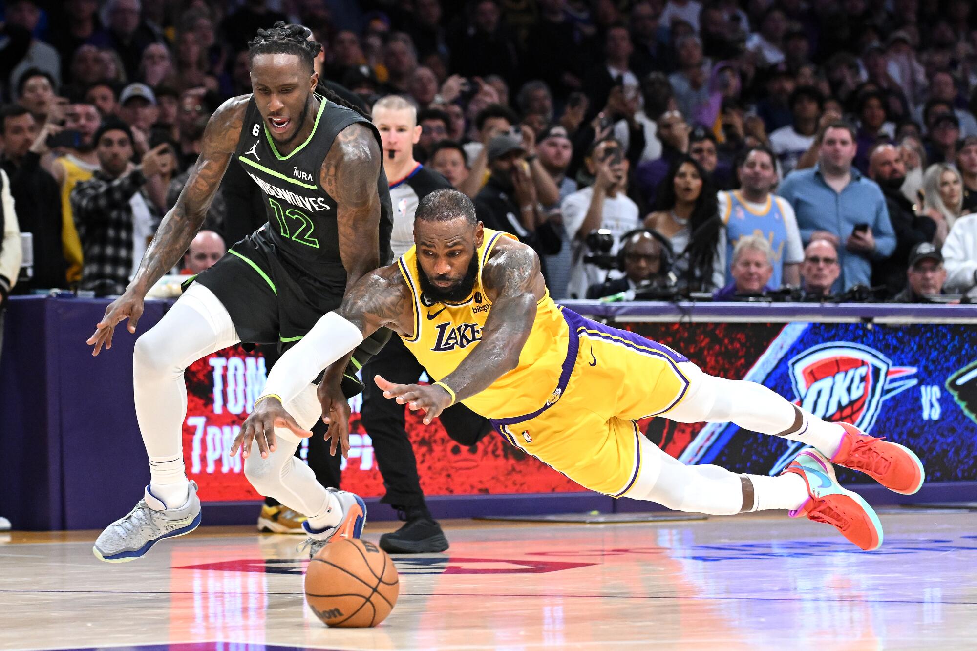 Lakers forward LeBron James dives for the ball in front of Timberwolves forward Taurean Prince