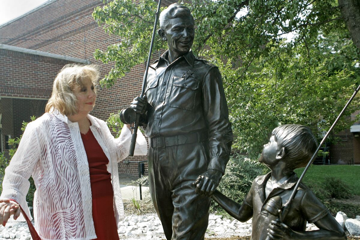 FILE - In this Sept. 6, 2007 file photo, actor Betty Lynn, who played Thelma Lou on "The Andy Griffith Show," pauses at a statue of Andy and Opie Taylor in Mount Airy, N.C. Lynn died Saturday, Oct. 16, 2021, after a brief illness, The Andy Griffith Museum in Mount Airy announced in a statement. She was 95. (AP Photo/Gerry Broome, File)