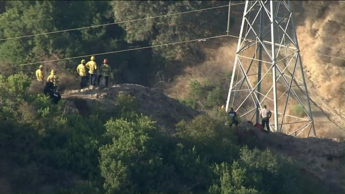 Los Angeles firefighters work Wednesday to retrieve a body found beneath power lines in Griffith Park.