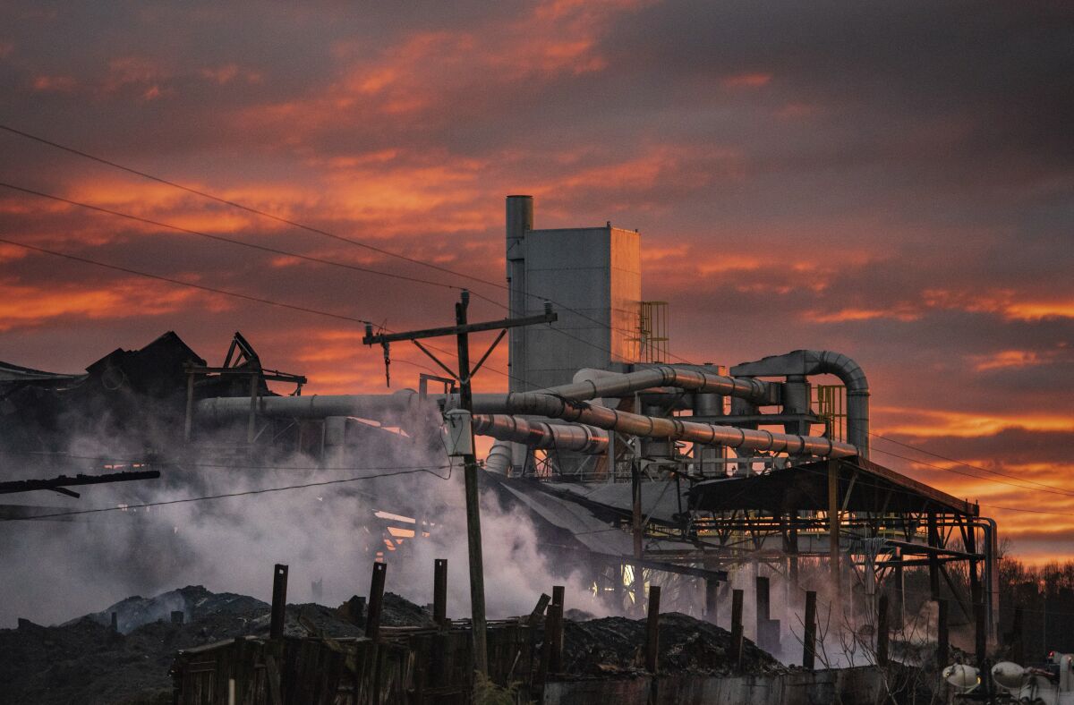 The sun sets at the site of the Winston Weaver Co. fertilizer plant fire on Friday, Feb. 4, 2022, in Winston-Salem, N.C. Crews have begun the cleanup process at the site. (Allison Lee Isley/The Winston-Salem Journal via AP)