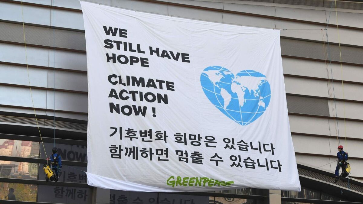 Greenpeace activists display a banner prior to a news conference on the latest U.N. climate change report in Incheon, South Korea, on Monday.