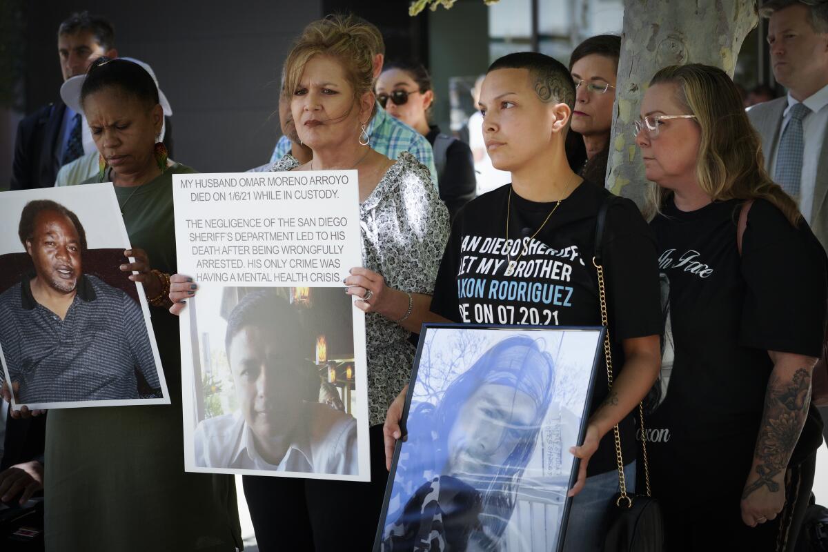 Four people hold posters displaying photos of their deceased loved ones