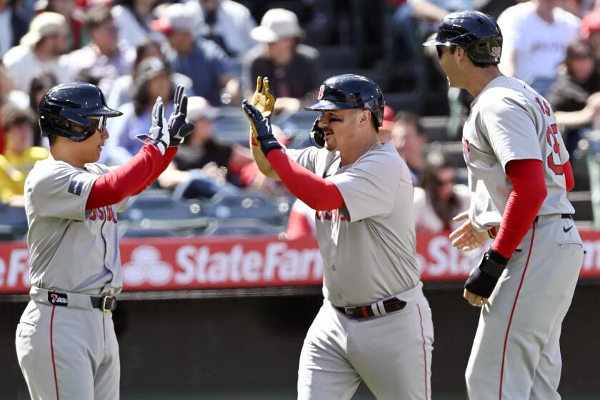 Masataka Yoshida, de los Medias Rojas de Boston, a la izquierda, saluda a Reese McGuire, al centro, con Triston Casas, a la derecha, después de que McGuire conectara un jonrón de tres carreras contra los Angelinos de Los Ángeles durante la sexta entrada de un juego de béisbol en Anaheim, California, el domingo 7 de abril de 2024. (AP Foto/Alex Gallardo)