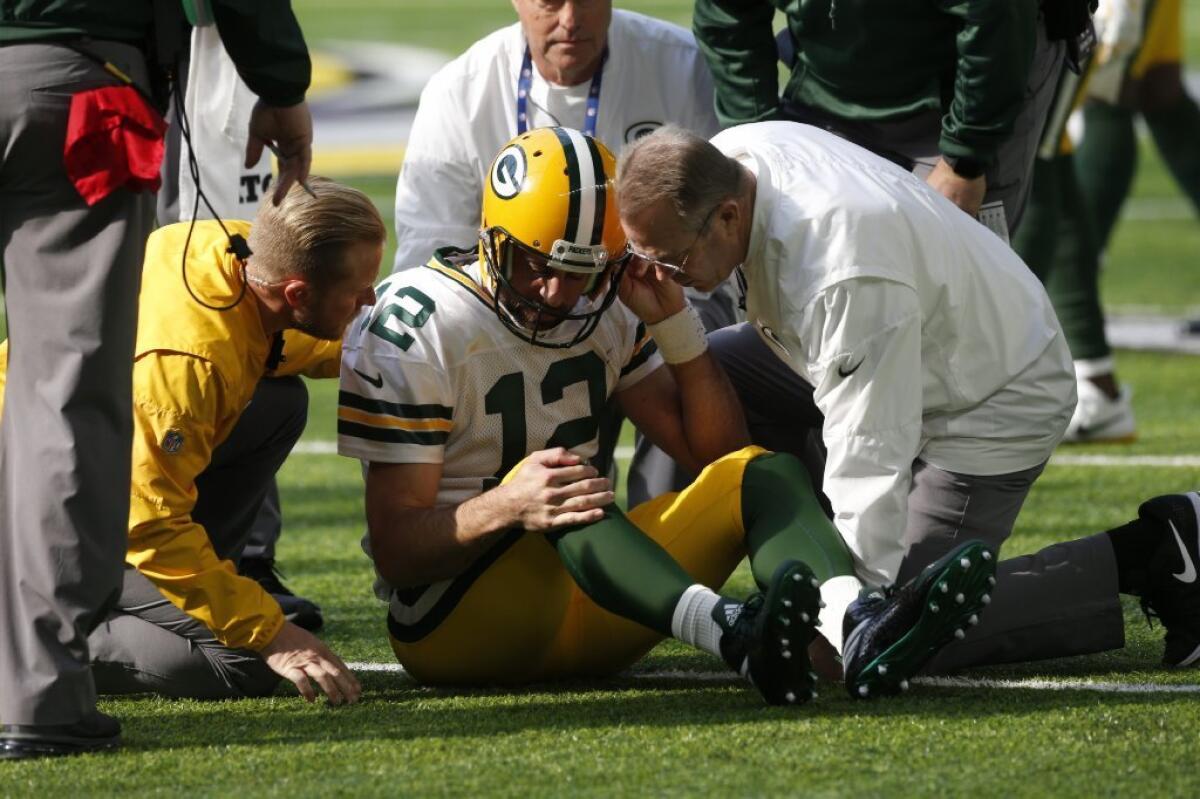 Green Bay Packers quarterback Aaron Rodgers is tended to on the field after suffering a shoulder injury on a hit from Minnesota Vikings linebacker Anthony Barr.