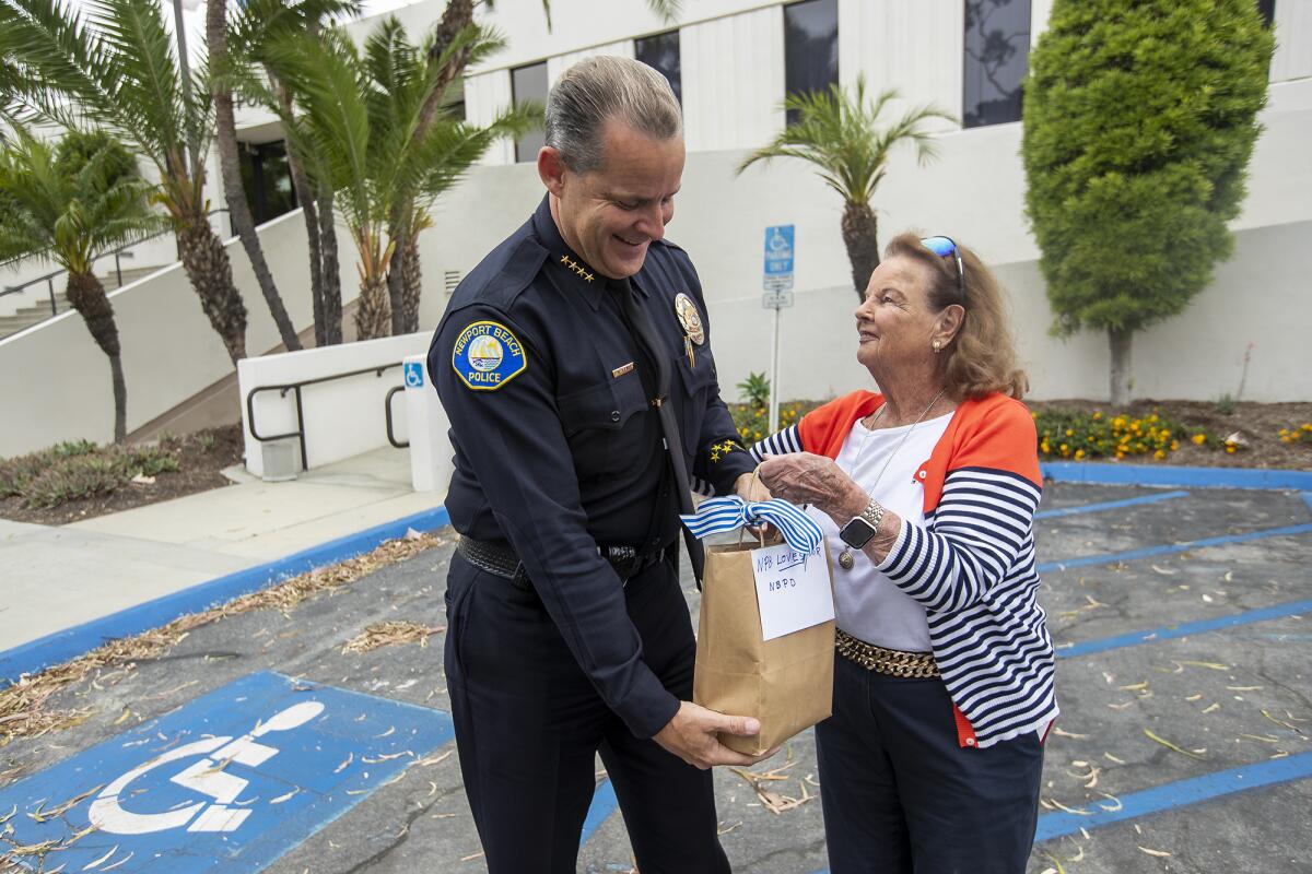 Dotty McDonald presents Newport Beach Police Department Chief Jon Lewis gift cards for the police department.