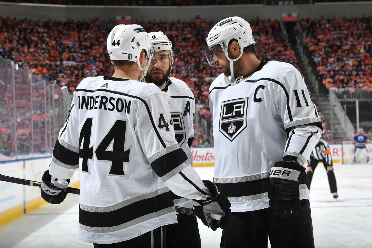 Kings captain Anze Kopitar, right, speaks with teammates Mikey Anderson (44) and Drew Doughty.
