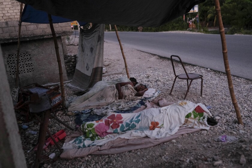 A nurse sleeps next to her daughter on the side of the road in Les Cayes, Haiti.