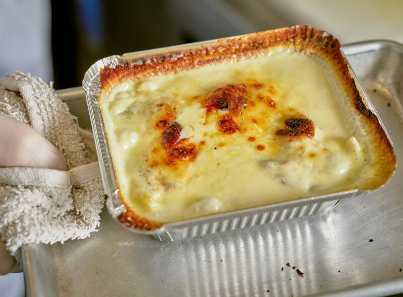 A rectangular foil pan holds creamy ravioli 