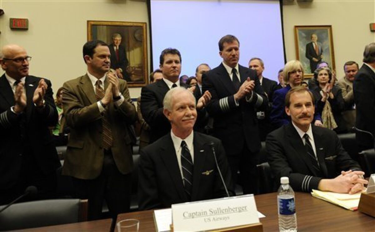 US Airways flight 1549 Capt. Chesley B Sullenberger III, seated, center, and First Officer Jeffrey B. Skiles, seated, right, receive a standing ovation on Capitol Hill in Washington, Tuesday, Feb. 24, 2009, as they prepared to testify before the House Transportation and Infrastructure Committee. (AP Photo/Susan Walsh)