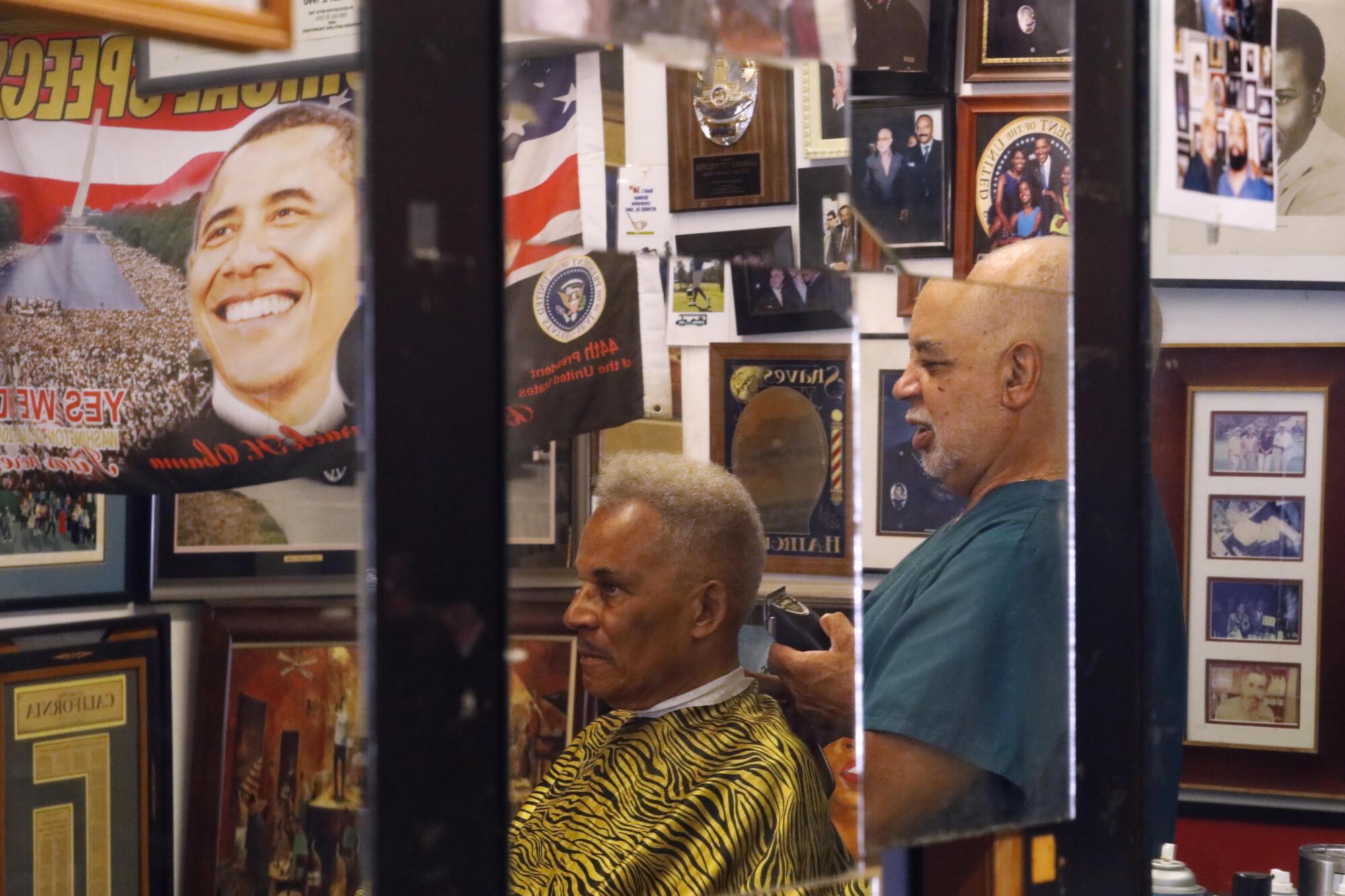 Lawrence Tolliver, reflected in a mirror, cuts a client's hair in 2019.