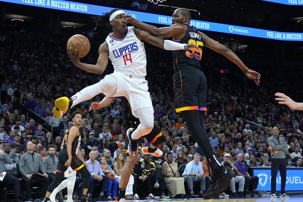 Clippers guard Terance Mann, left, is fouled by Suns forward Kevin Durant as he leaps into the air to make a pass.